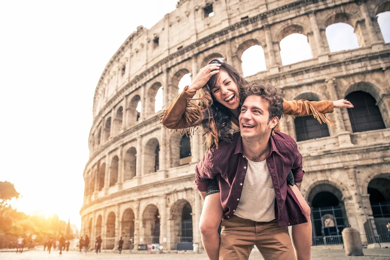 Pareja viajando frente al Coliseo de Roma durante un viaje a Italia